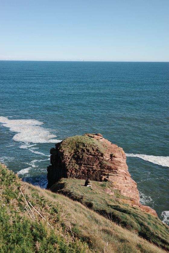 Coastal Walk: Isolated red sea stack above surf