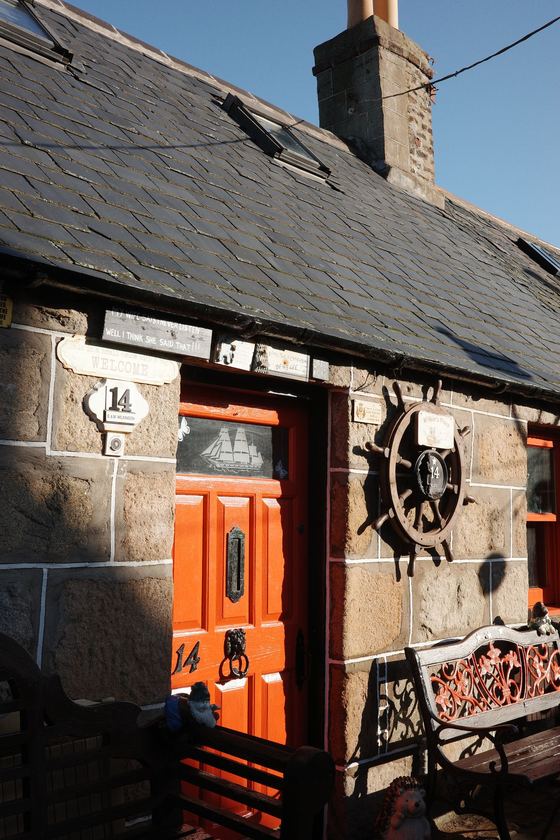 Footdee: Bright orange door with nautical decorations