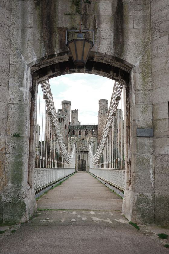 Conwy and Llandudno: Suspension bridge framed through stone arch