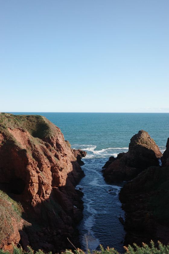 Coastal Walk: Waves entering narrow red rock gorge