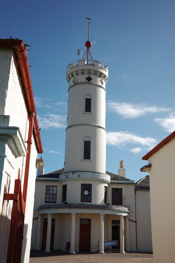 Docks: White lighthouse framed by harbour buildings