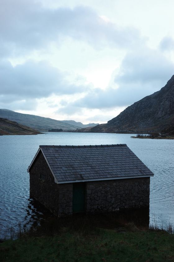 Snowdonia and Llanfairpwll: Lakeside boathouse against distant mountains