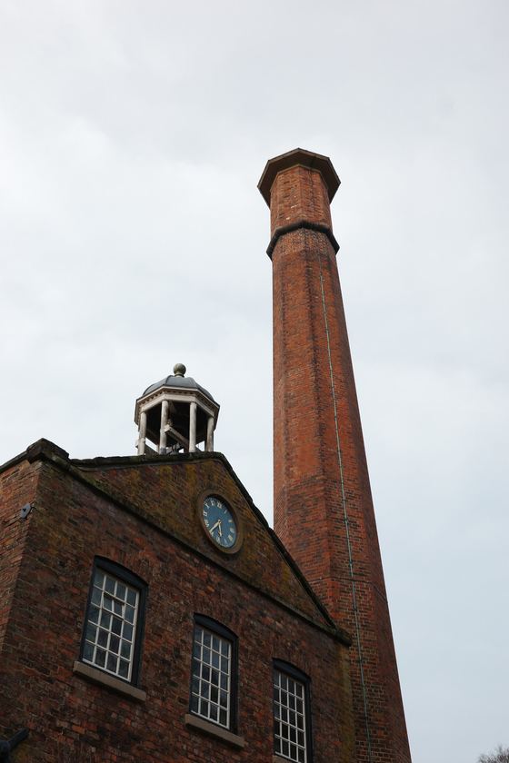 Manchester: Mill chimney rising above brick facade